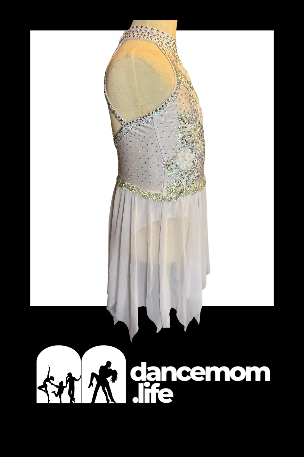 A shimmering silver and white dance leotard adorned with sparkling rhinestones along the neckline, waistband, and a floral embellishment on the bodice.
