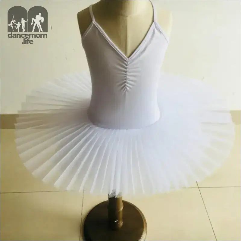 White ballet tutu dress with spaghetti straps and a pleated skirt on a display stand.