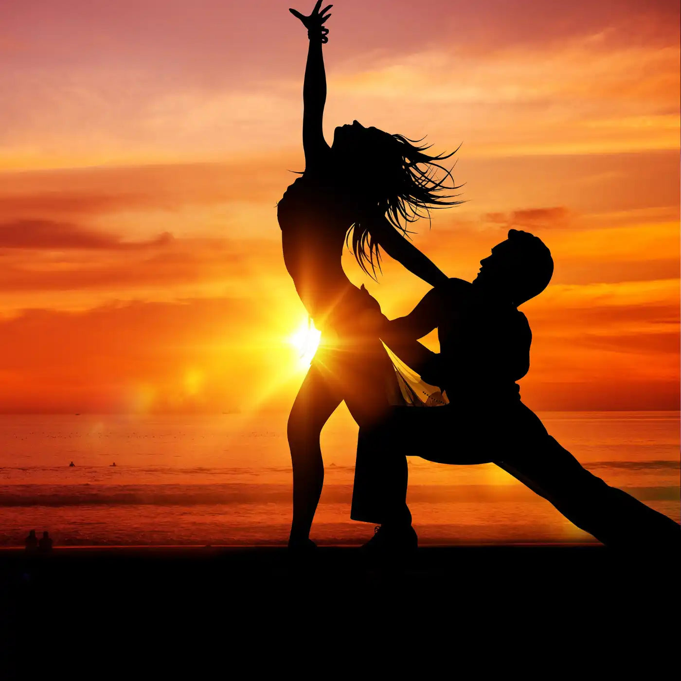 Silhouette of a dancing couple against a vibrant sunset sky.