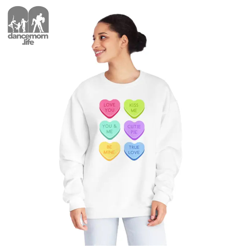 White sweatshirt featuring six colorful candy heart designs with text messages printed on them.