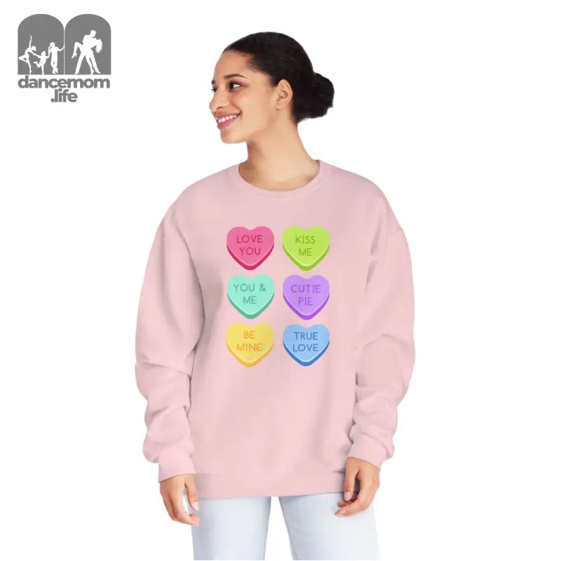 Pink sweatshirt featuring colorful candy heart designs with text.