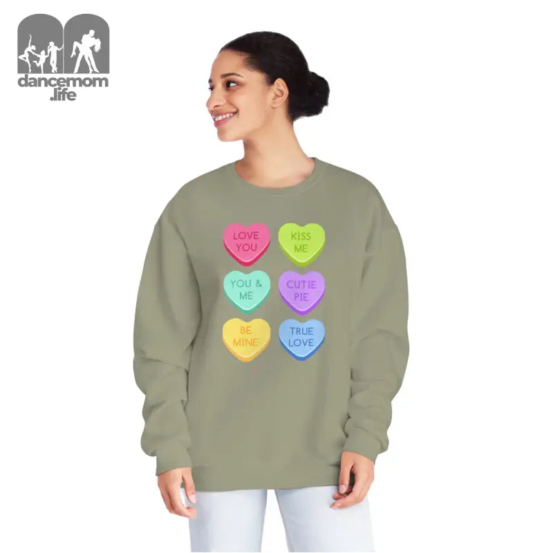 Sage green sweatshirt featuring colorful candy heart designs with messages printed on them.